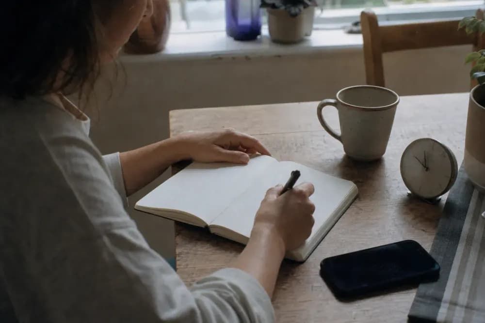 Adult reviewing a blank sleep diary at a kitchen table in morning light